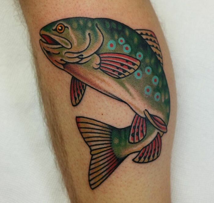 American traditional tattoo of a vibrantly colored fish on a person's leg.