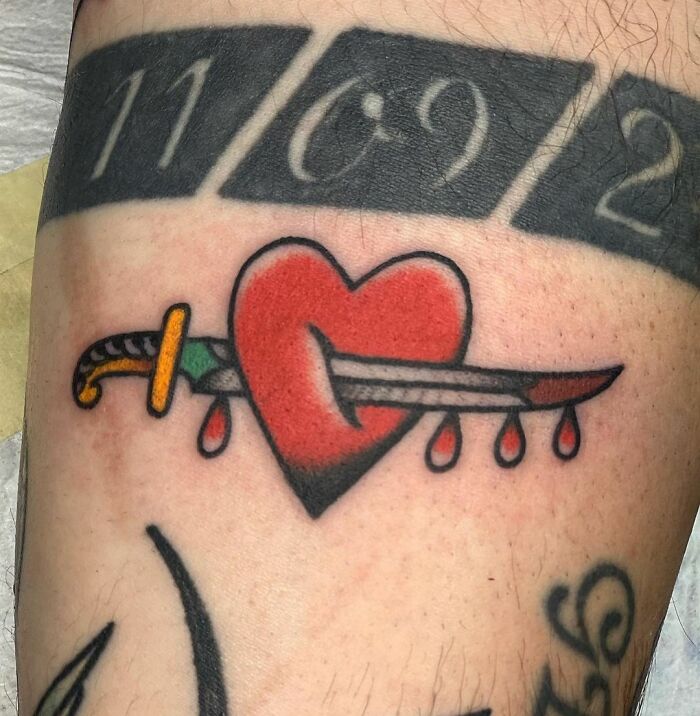 American traditional tattoo with a red heart pierced by a dagger and dripping blood.