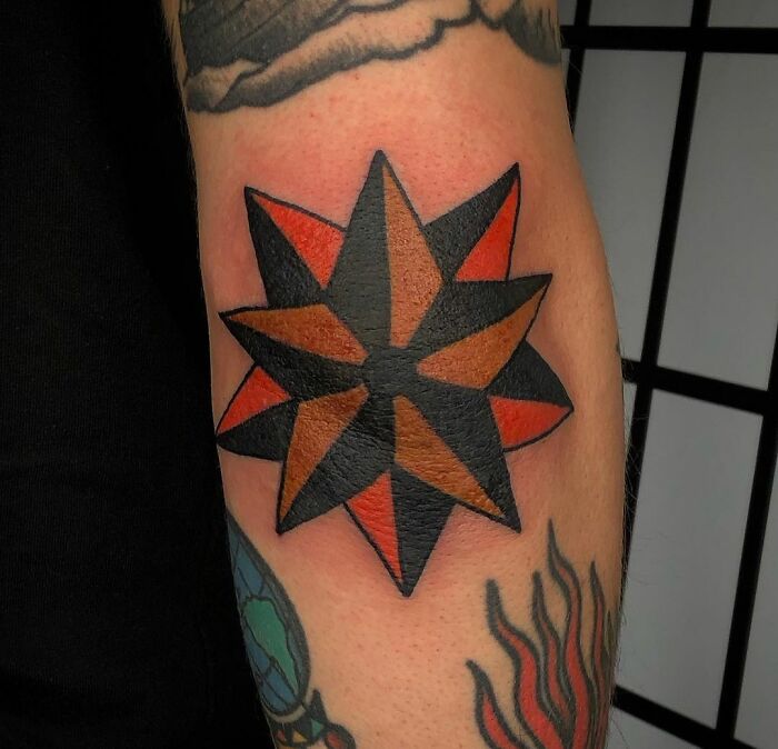 A bold American traditional tattoo design featuring a black and red star on a person's arm.