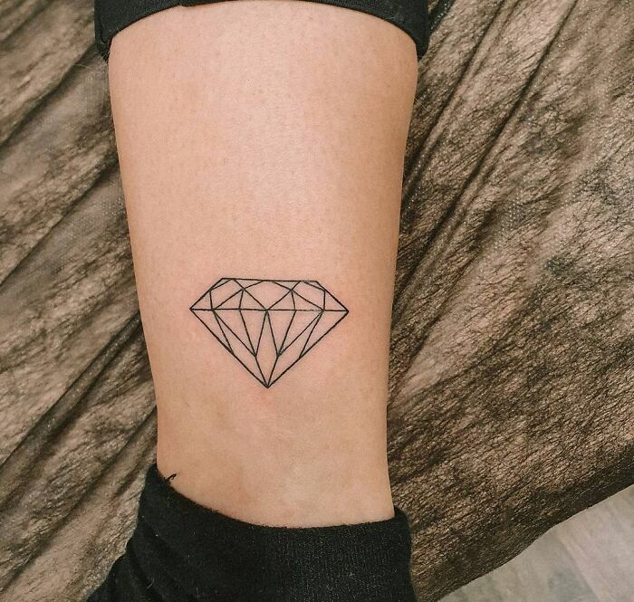Minimalist diamond ankle tattoo on skin.