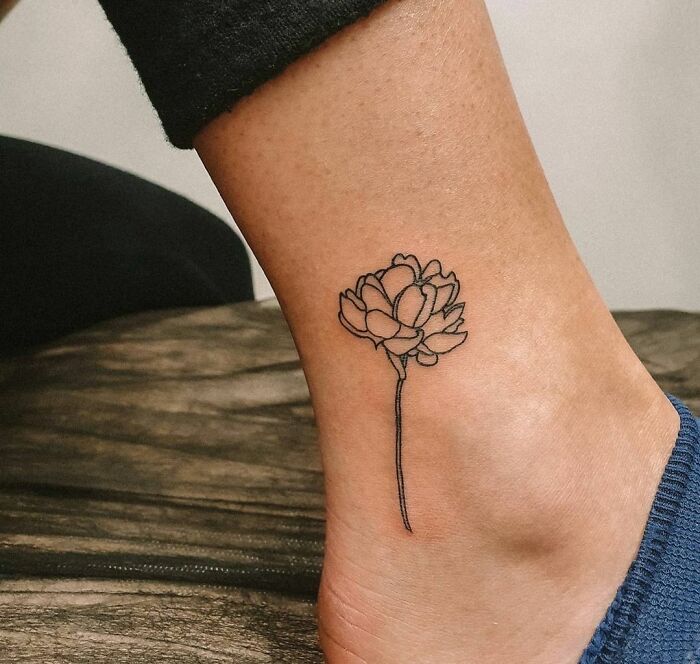 Minimalist flower ankle tattoo design on skin.