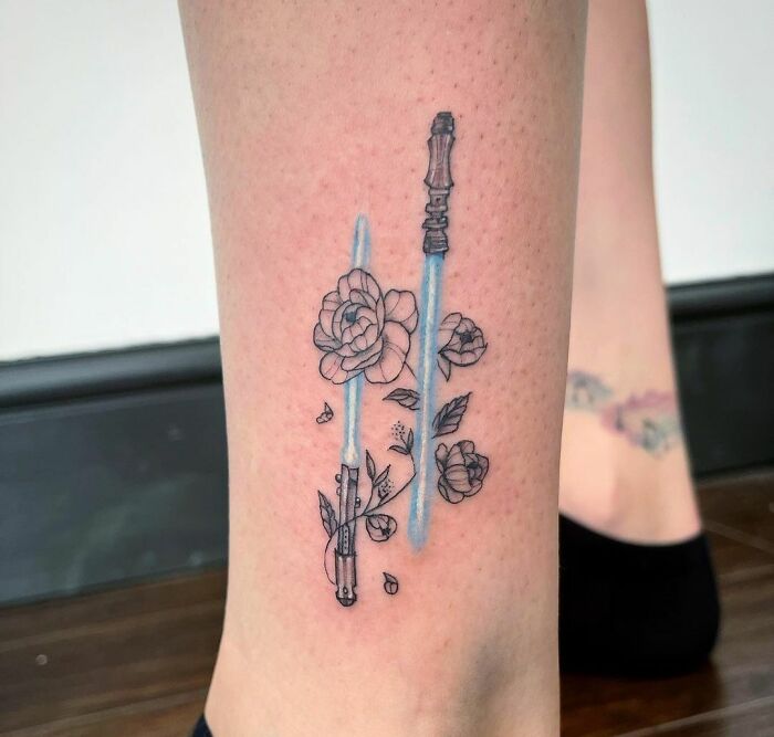Ankle tattoo with lightsabers and roses, blending floral and sci-fi designs.