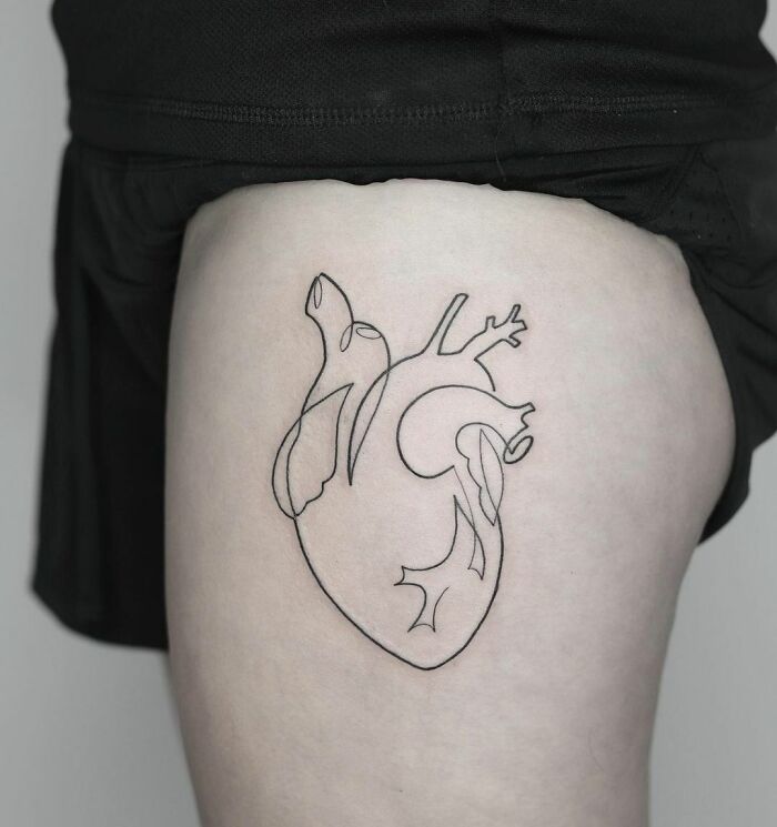 Fine-line single-line tattoo of an anatomical heart on skin.
