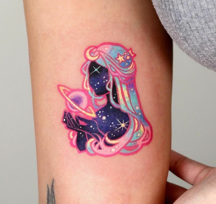 Colorful space tattoo of a cosmic figure with galaxy hair, holding a planet, blending pinks and blues.