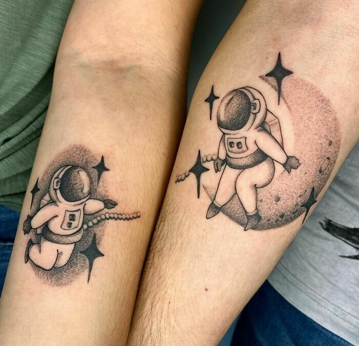 Matching space tattoos of astronauts with stars, depicting cosmic adventure art on forearms.