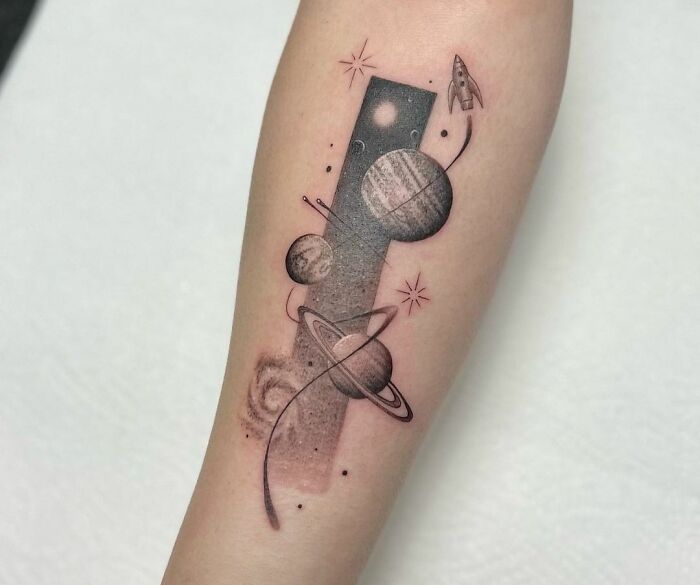 Space tattoo featuring planets and a rocket on an arm.