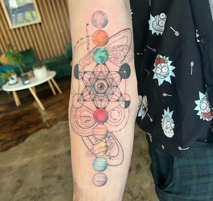 Colorful space tattoo on an arm with planets and geometric designs.