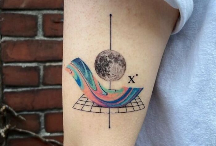Space tattoo featuring abstract design with colorful wave, planet, and geometric grid on arm.