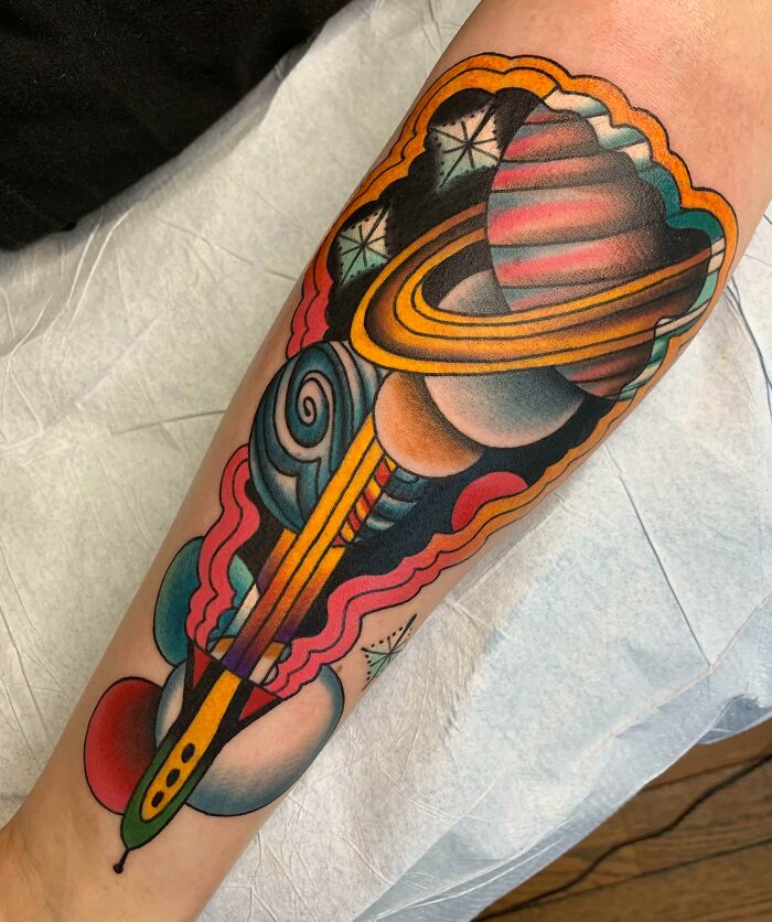 Colorful space tattoo featuring planets and stars on an arm.