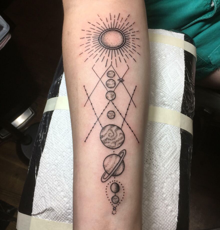Space tattoo featuring planets and celestial designs on a forearm.