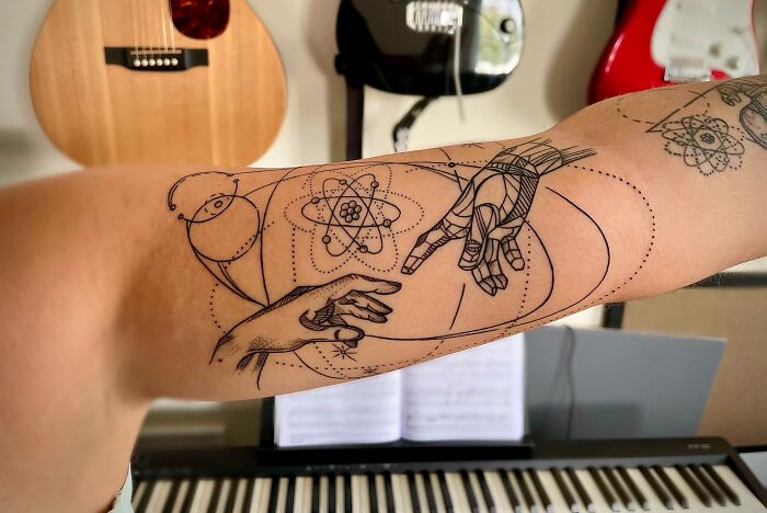 Arm with a cool space tattoo featuring cosmic designs and geometric elements, displayed in an artistic room setting.