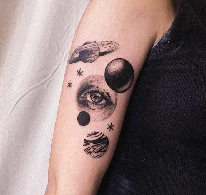 Space tattoo with planets and an eye design on an arm, showcasing cosmic art.