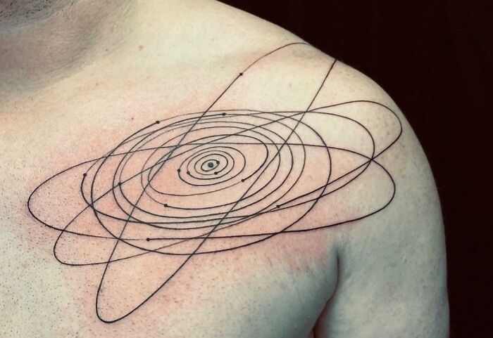 Man with a detailed orbital design tattoo on his shoulder, showcasing cool space tattoo art.