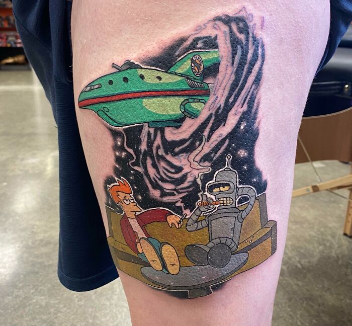 Colorful space tattoo featuring cartoon characters and a spaceship on a person's thigh.