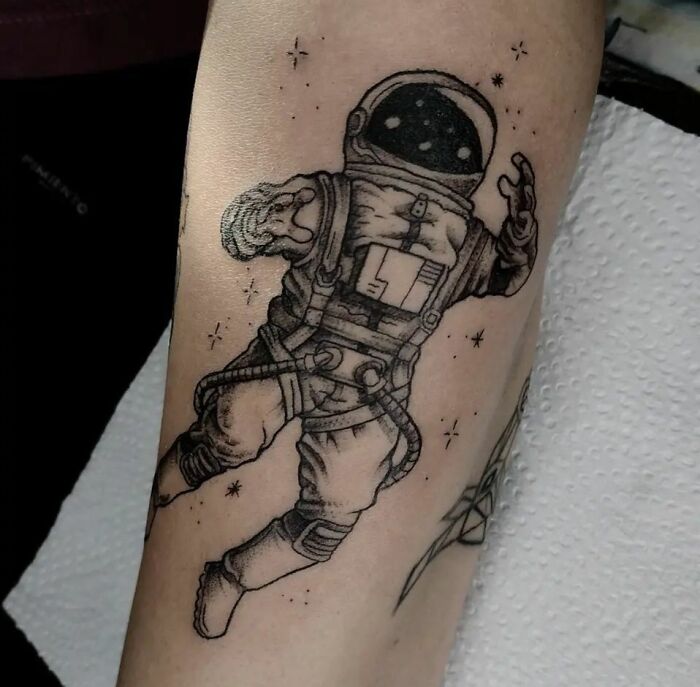 Astronaut tattoo on arm with cosmic details, showcasing cool space art.