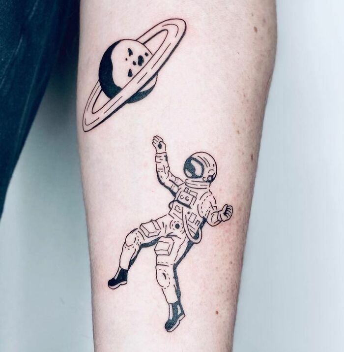 Astronaut and Saturn tattoo, showcasing cool space art on a forearm.