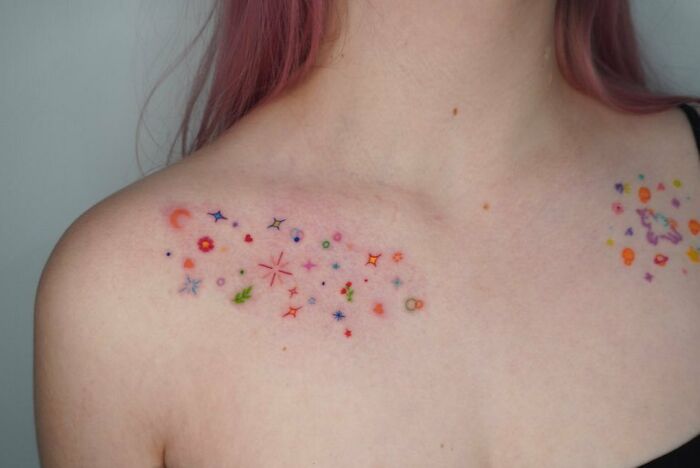 Colorful space tattoo with stars and planets on a person's collarbone.