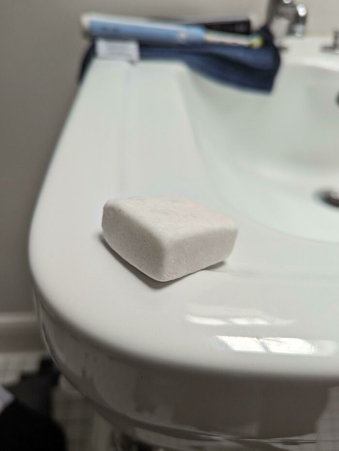 Small white mysterious object resting on the edge of a bathroom sink, part of people stumbling upon unknown items collection.