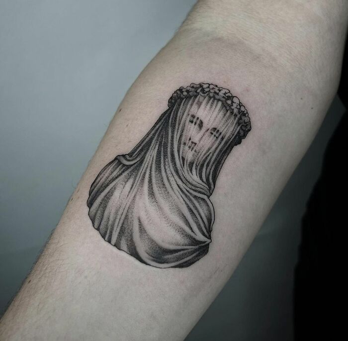 Gothic tattoo of veiled face on forearm, featuring intricate shading and a mysterious, ethereal design.