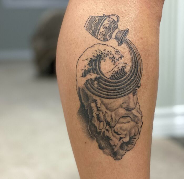 Zodiac tattoo depicting Aquarius with a water jug pouring waves over a bearded head.