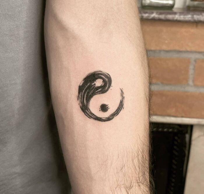 Yin Yang tattoo in black ink on forearm, symbolizing duality and balance in life.
