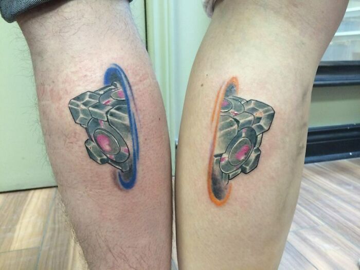 Matching video game tattoos on calves, each featuring a portal design.