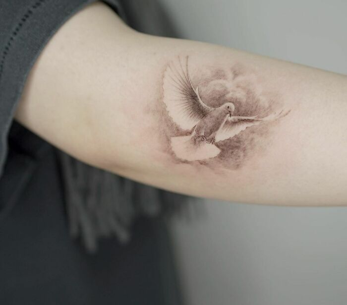 Dove tattoo on a person's elbow, showcasing intricate shading and detail.