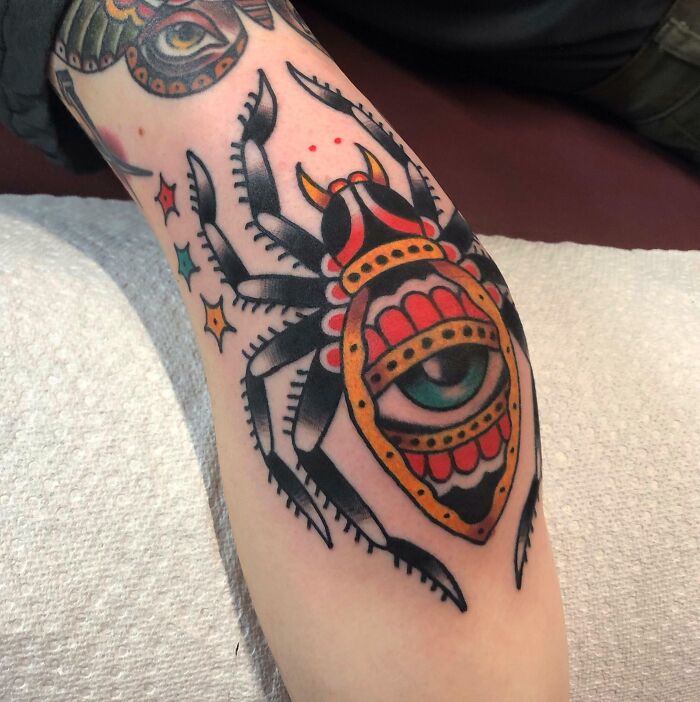 Unique elbow tattoo featuring a colorful spider design with an eye motif.