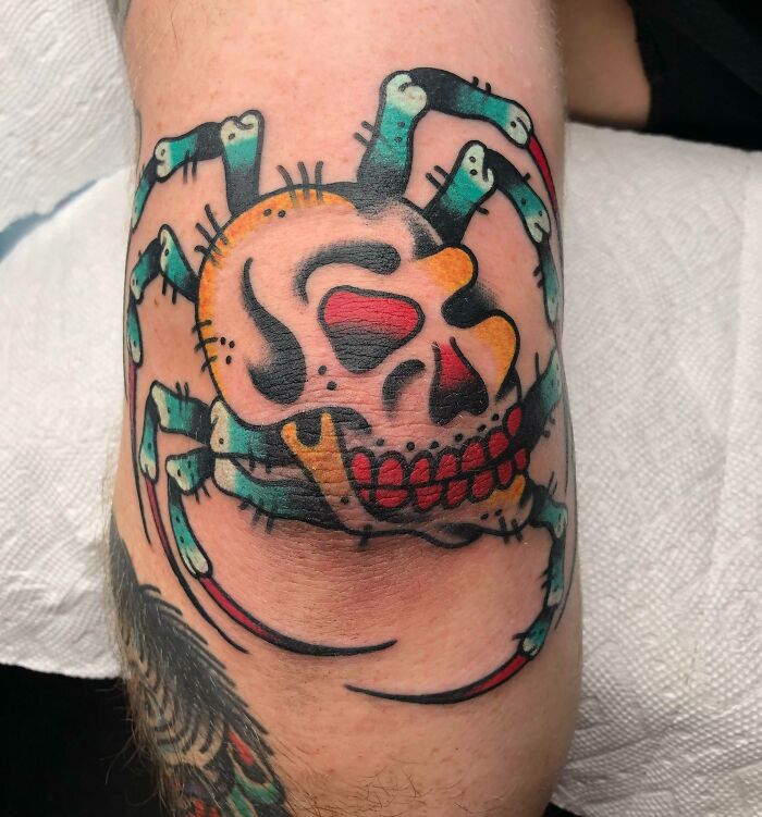 Colorful spider and skull elbow tattoo design showcasing bold outlines and vivid details.