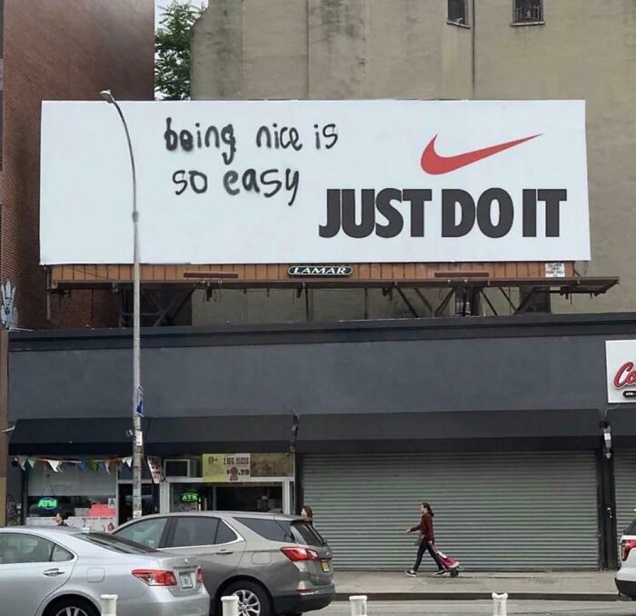 Billboard with Nike logo altered by vandalism for humanity reading being nice is so easy above Just Do It slogan.