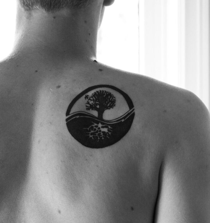 Back tattoo featuring a yin yang design with a tree, symbolizing duality and balance.