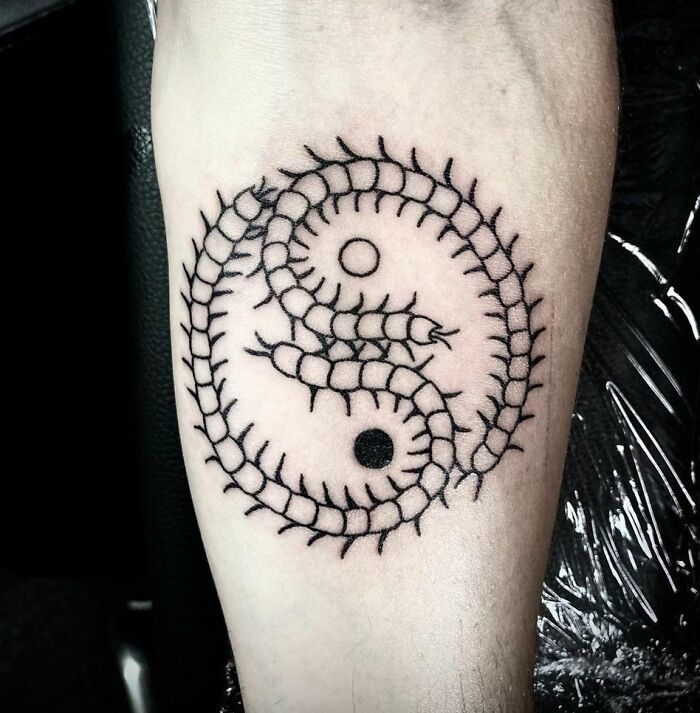Intricate yin yang tattoo featuring centipede design, symbolizing the duality of life on forearm.