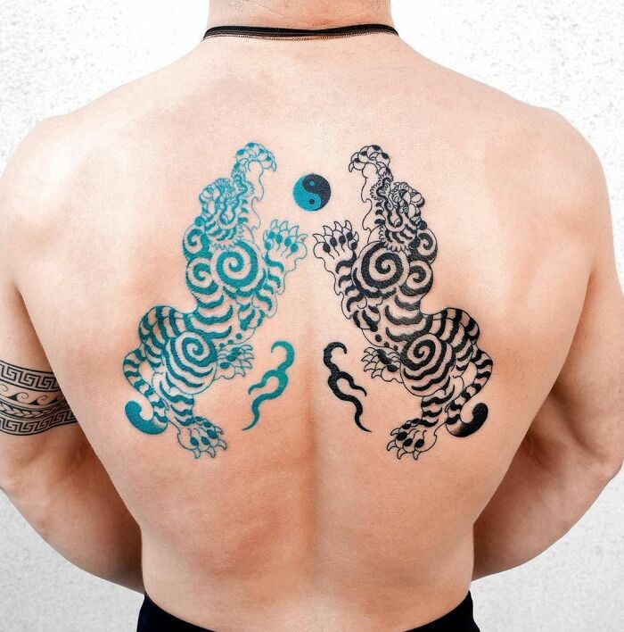 Back tattoo of artistic yin yang with vibrant swirling tigers.
