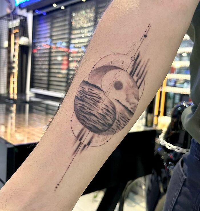 Geometric yin yang tattoo on forearm, symbolizing duality with intricate details.