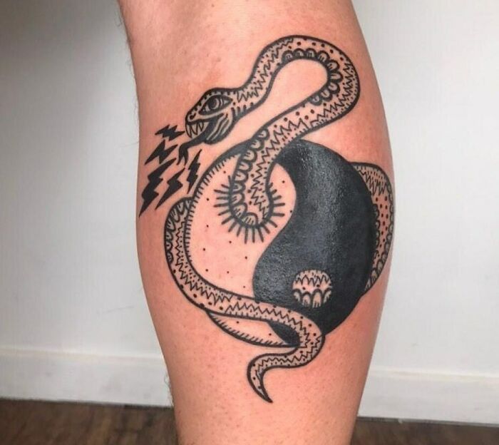 Snake intertwined with a yin yang tattoo, symbolizing life's duality.