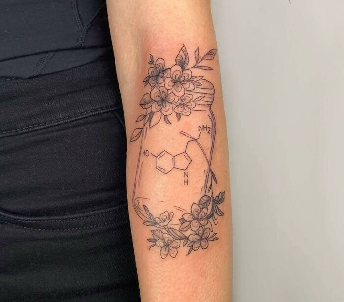 Floral science tattoo featuring a serotonin molecule on the forearm.
