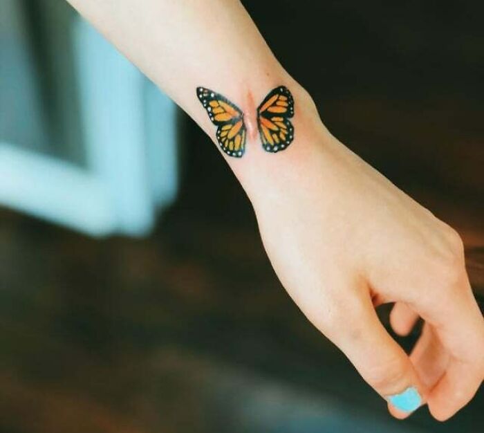Colorful butterfly tattoo on a wrist, showcasing vibrant design.