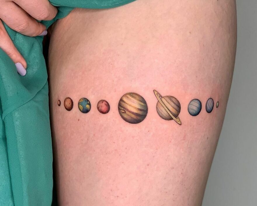 Solar system tattoo featuring planets in a line on skin, showcasing outer space cool design.