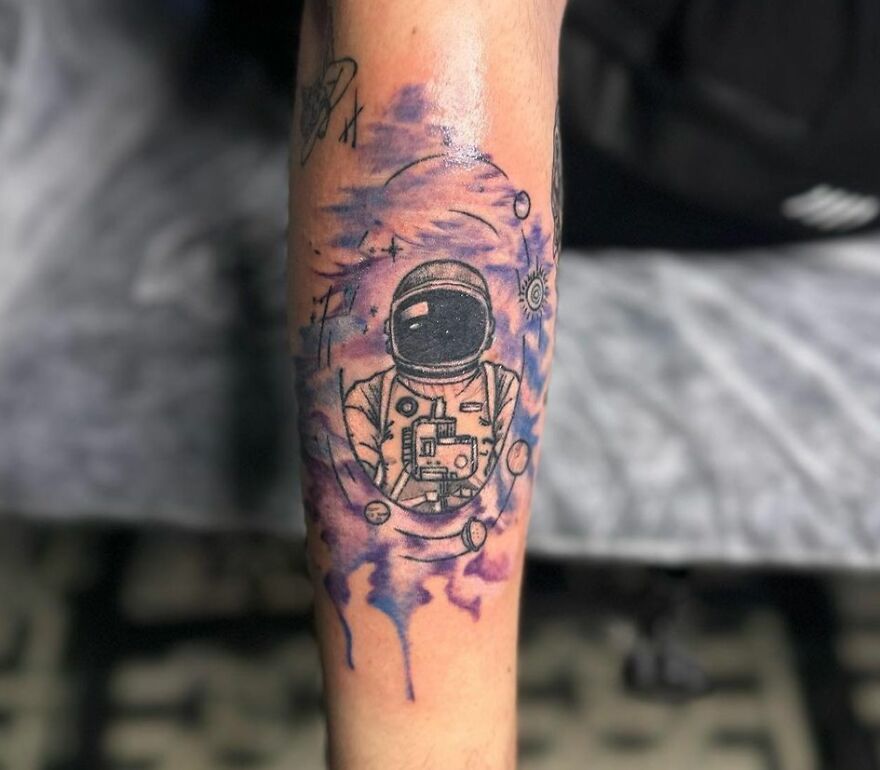 Astronaut space tattoo on arm with planets and stars.