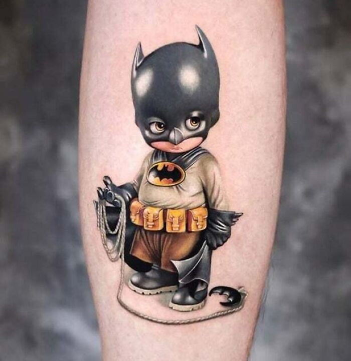 Cartoon tattoo of a small character wearing a Batman-themed costume, inspired by animated shows.