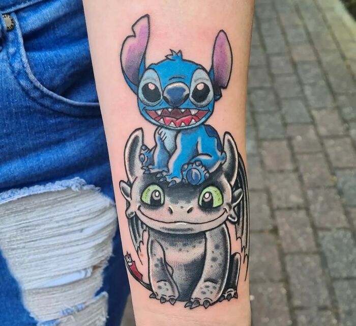 Cartoon tattoo featuring vibrant Stitch And Toothless characters from favorite animated shows on a person's forearm.