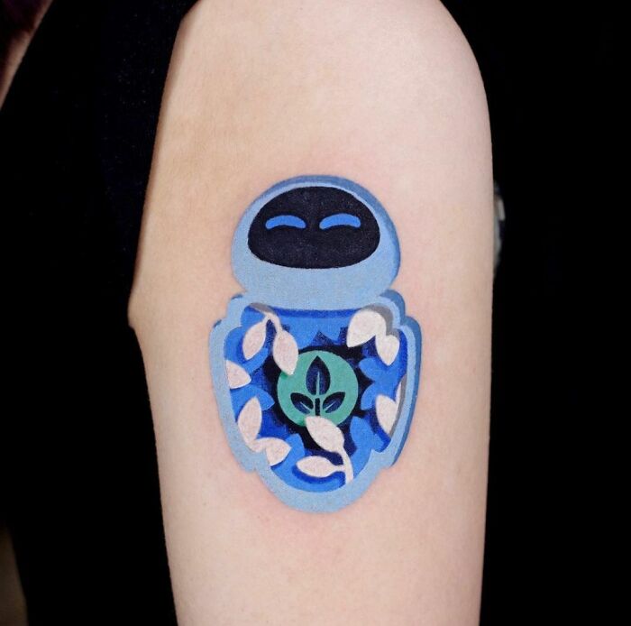 Cartoon tattoo of a blue robot with a leaf design on an arm, inspired by animated shows.