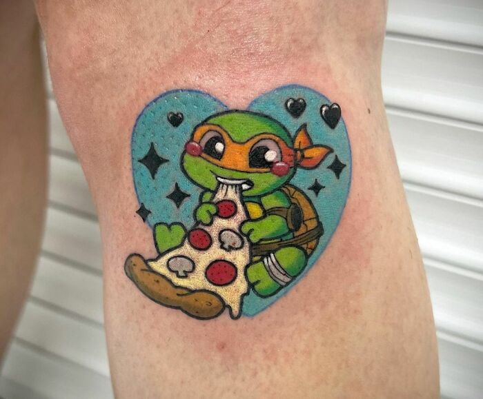 Cartoon tattoo of a turtle eating pizza, inspired by animated shows, with a heart and stars background.