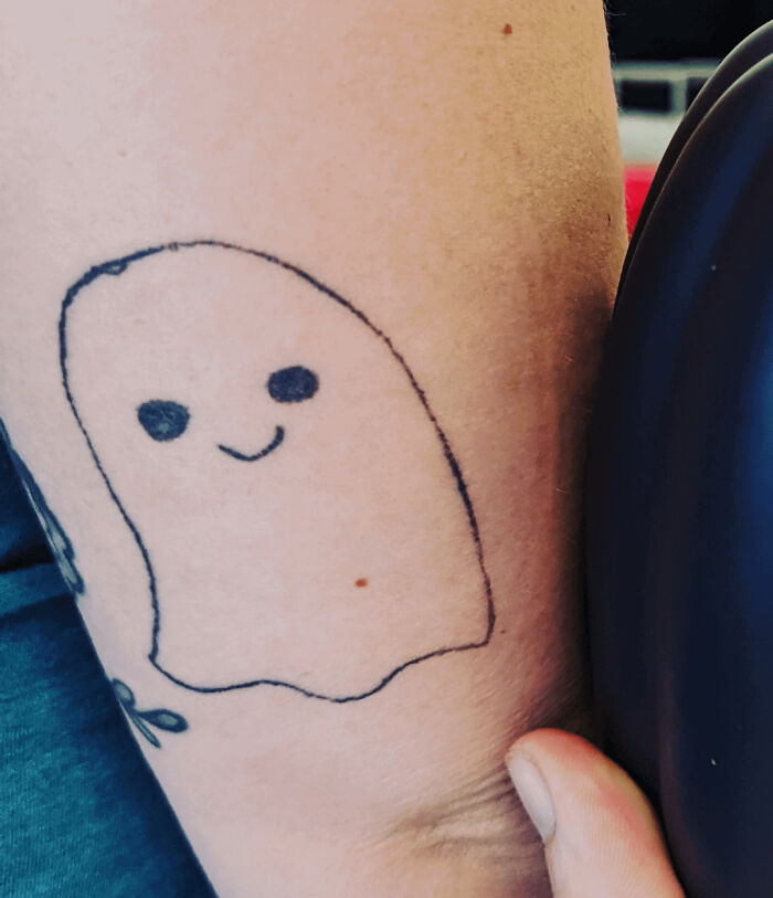 Simple cartoon ghost tattoo on arm, showcasing a need for better tattoo artist research.