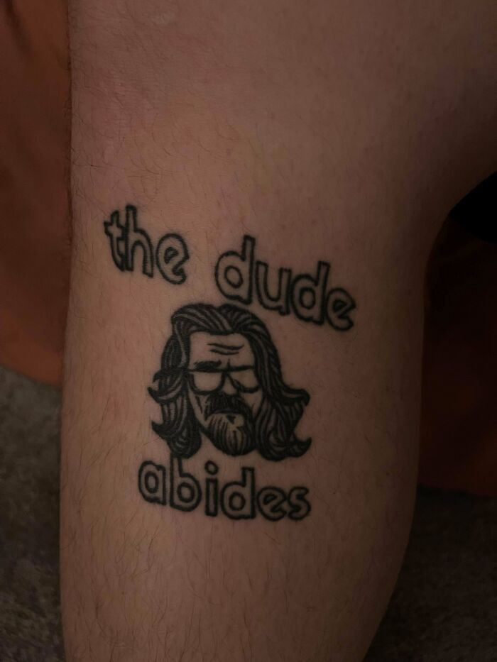 Tattoo of a bearded man with sunglasses, text reads "the dude abides," indicating poor artist research.
