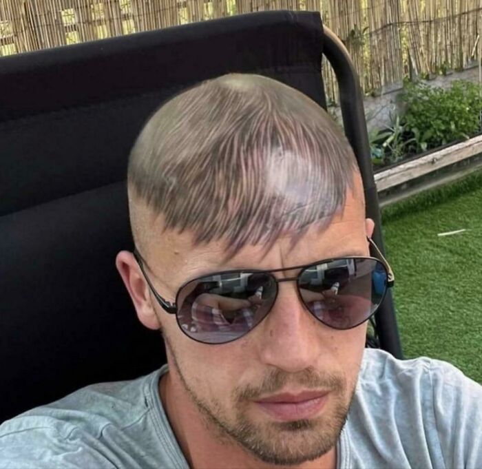 Man with sunglass and tattoo of bangs on his shaved head, highlighting tattoo artist choice.