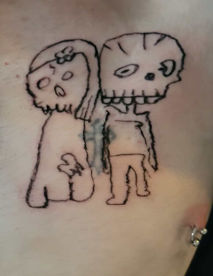 Poorly drawn tattoo depicting two cartoon-like skeleton figures.
