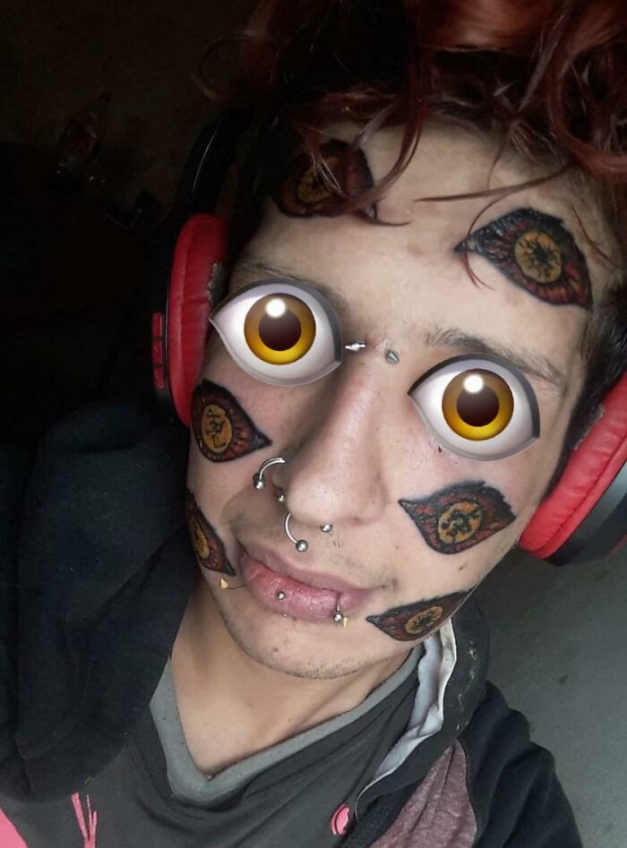 Man with facial tattoos and piercings wearing red headphones.