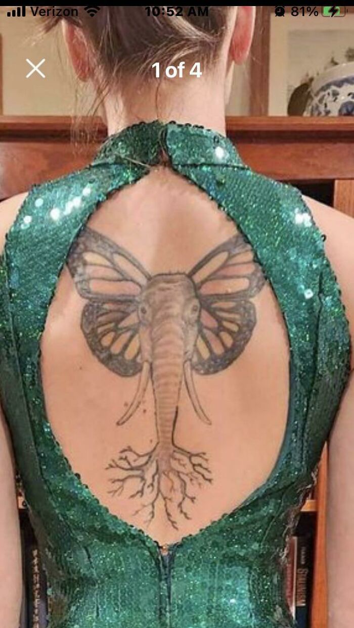 Woman showing an elephant-butterfly tattoo on her back in a green dress.