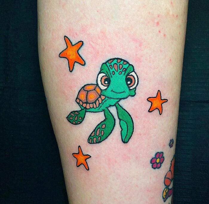 Cartoon tattoo of a green turtle with orange stars, inspired by animated shows.